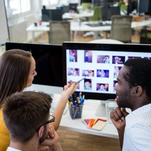 Group of graphic designers interacting over computer in office